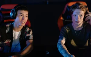 Friends holding game controllers and playing a video game together in front of a TV