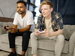 Two friends playing console games on a couch