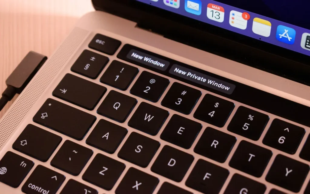 Close-up of hands typing a web address on a laptop keyboard